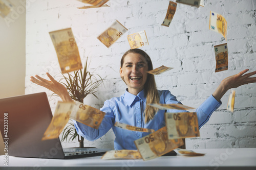 successful cheerful business woman throwing euro banknotes in office. falling money. wealth and passive income concept