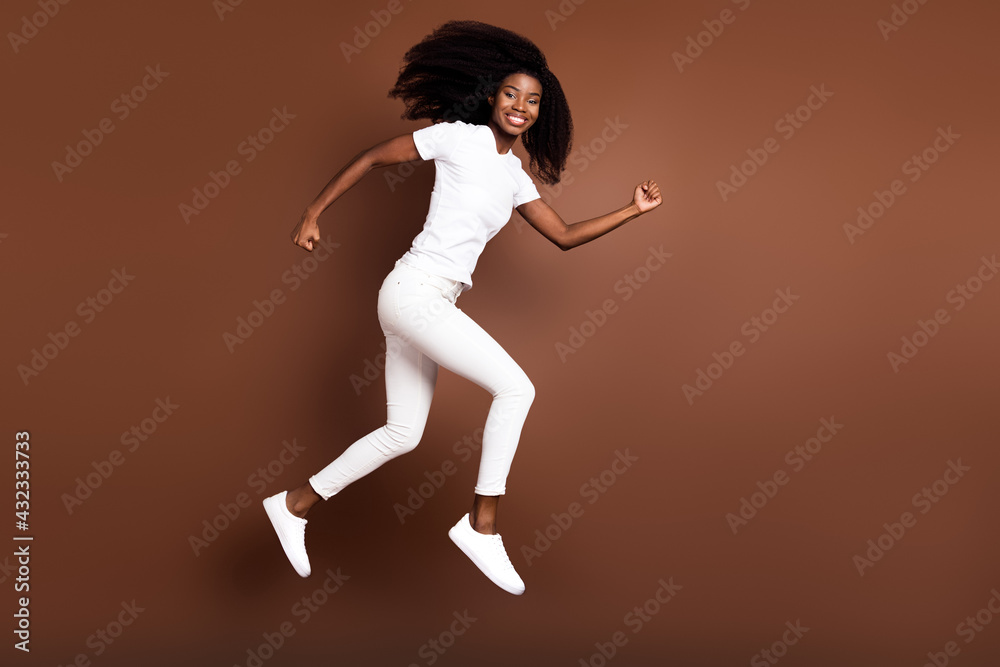 Full length body size view of attractive cheerful energetic girl jumping running isolated over brown color background