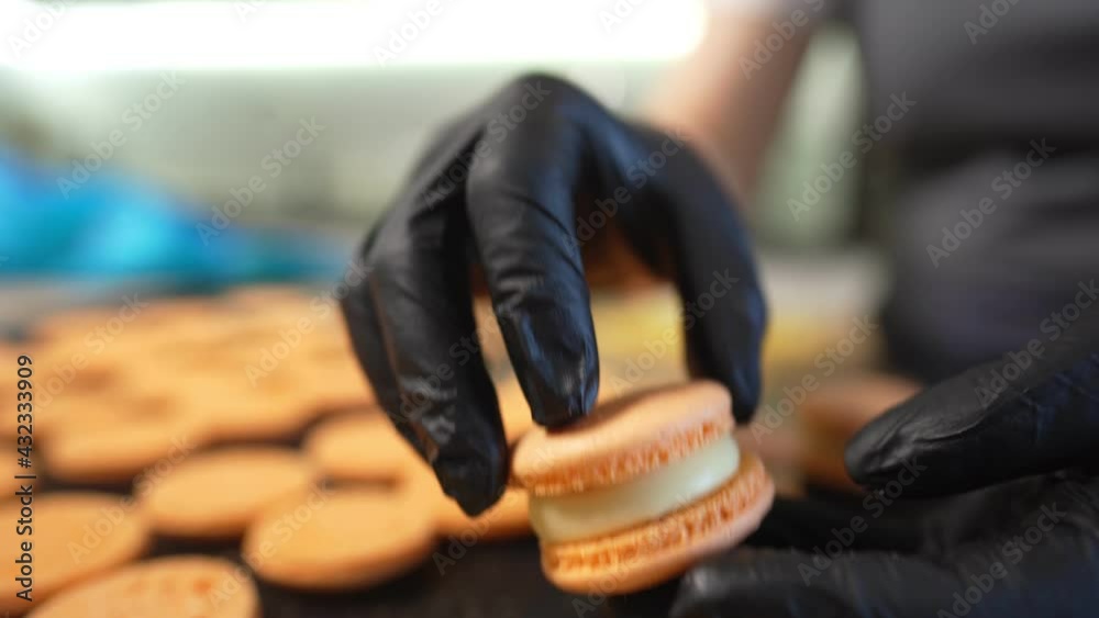 Process Of Making macaroon at home. Shot of hands of female pastry chef holding white macaron with ganache and squeezing red fruit jam from bag. Nature pastry macaroons. High quality 4k footage