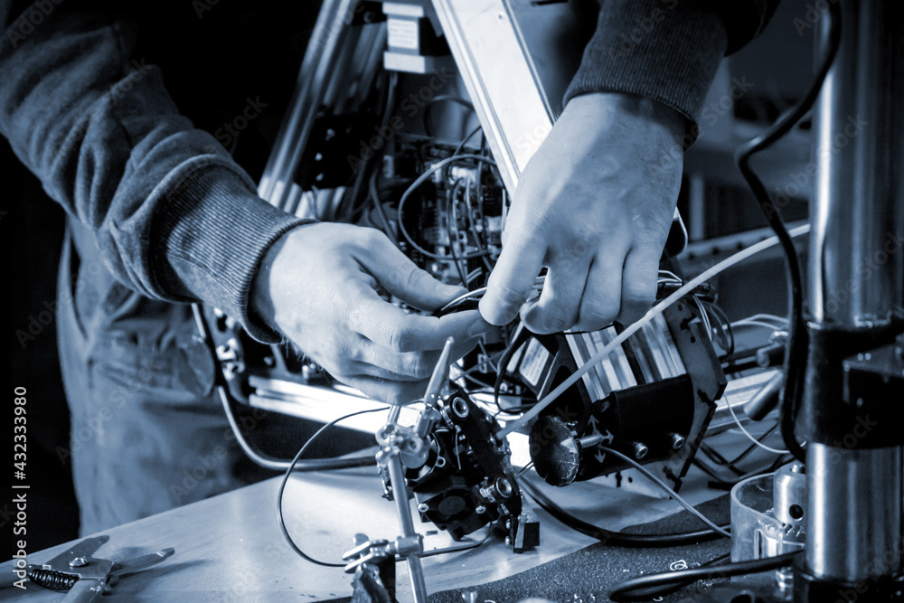 Two male masters work in the workshop with electronics, wires, 3d printer. Two male masters work in the workshop with electronics, wires, 3d printer.