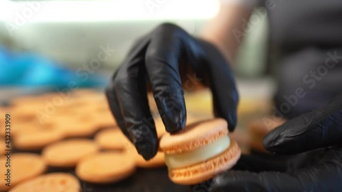 Process Of Making macaroon at home. Shot of hands of female pastry chef holding white macaron with ganache and squeezing red fruit jam from bag. Nature pastry macaroons. High quality 4k footage photo