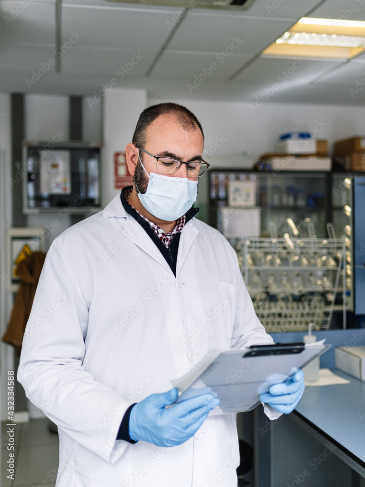 chemist reviewing a work report. Lab technician with protective mask looking at technical data. photography vertical