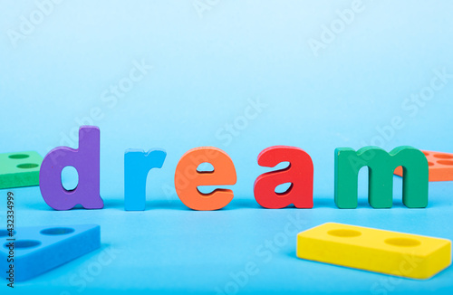 Dream word written with wooden alphabets blocks on blue chart kids children background