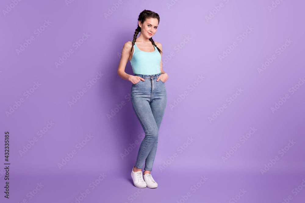 Full length body size view of attractive cheery shy girl holding hands in pockets isolated over violet purple color background Full length body size view of attractive cheery shy girl holding hands in pockets isolated over violet purple color background