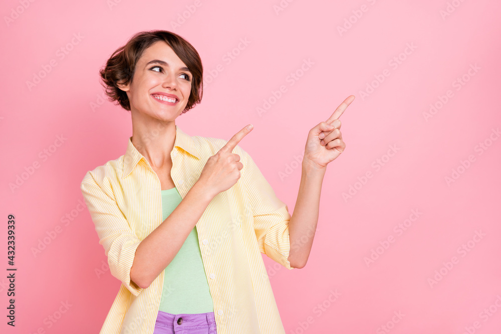 Photo of charming cute young lady dressed yellow shirt looking pointing two fingers empty space isolated pink color background Photo of charming cute young lady dressed yellow shirt looking pointing two fingers empty space isolated pink color background
