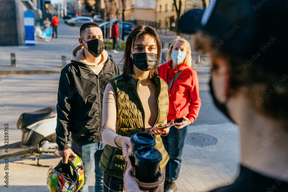 Obraz premium New normal and Social distancing when go back to work after coronavirus covid 19 spread concept. People wearing mask keep distance when waiting near local shop or cafe.