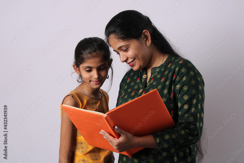 Indian girl studying with mother or teacher and having fun learning