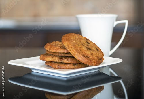 cookies on a white plate with a cup on a kitchen table  