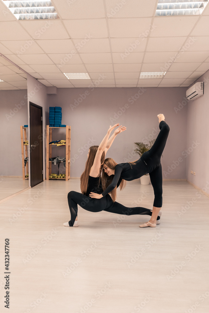 Obraz premium Beautiful young woman is engaged in gymnastics in the gym. The athletic body of the girl is covered with tight-fitting yoga clothes.
