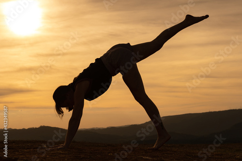 Silhouette of a young woman exercising alone on the mountains with a beautiful sunset