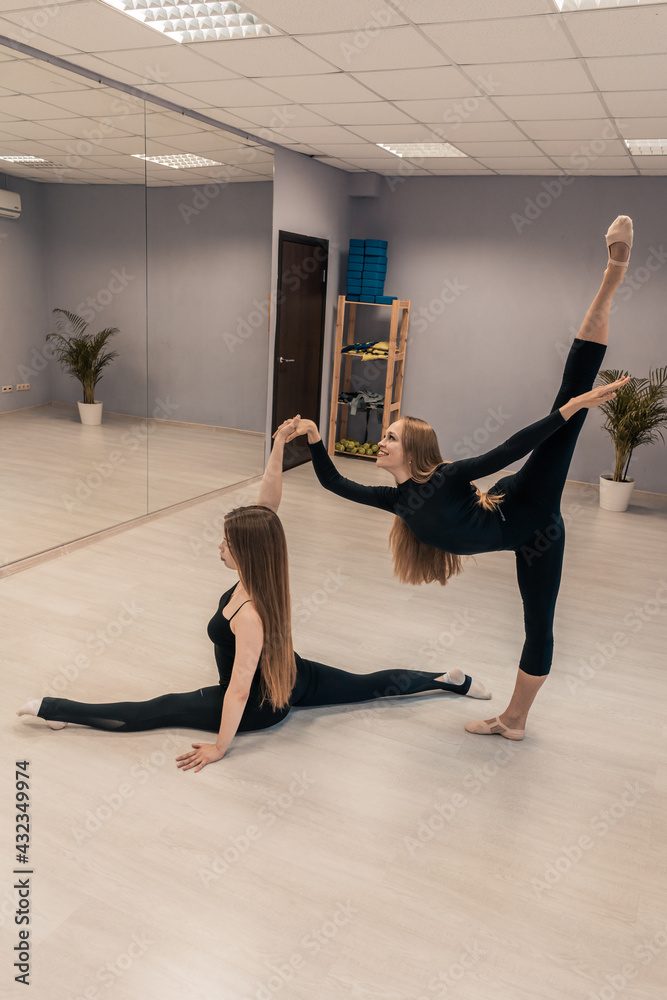 Obraz premium Beautiful young woman is engaged in gymnastics in the gym. The athletic body of the girl is covered with tight-fitting yoga clothes.