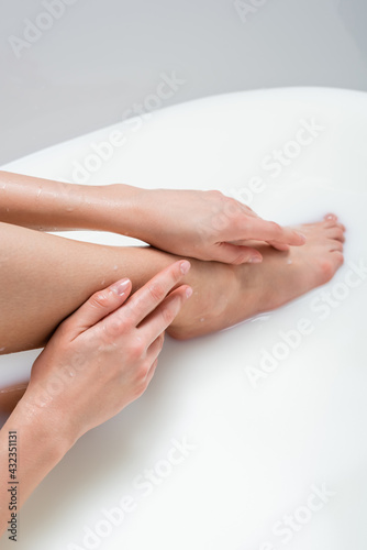 partial view of woman touching leg while bathing in milk.