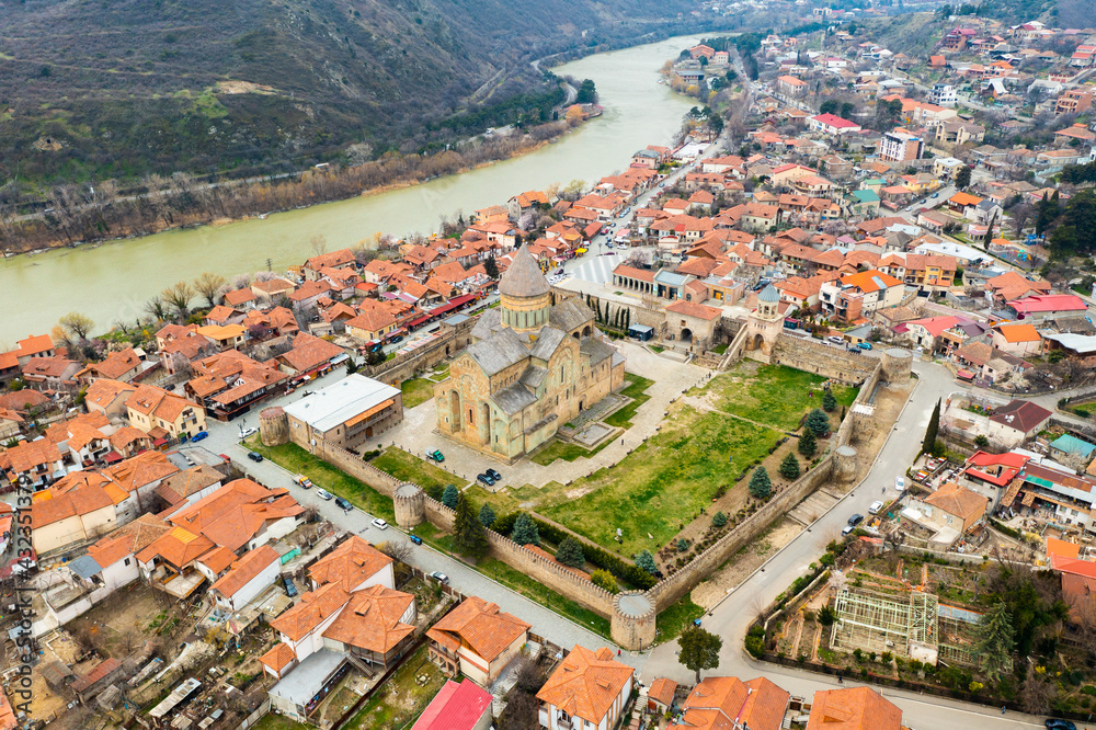 View from drone of ancient Orthodox Svetitskhoveli Cathedral against background of spring cityscape of Mtskheta in valley of Caucasus mountains in Georgia