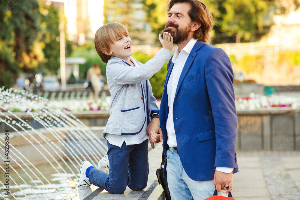 Happy dad and son fooling on a walk. Businessman with kid having fun together outdoors. Happy father's day.
