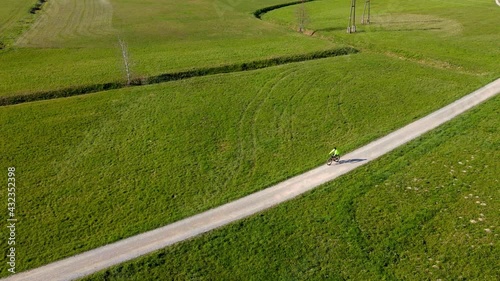 Man cycling along gravel road across the meadow.