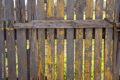 Closeup of old rotten wooden garden fence on background with green grassland..