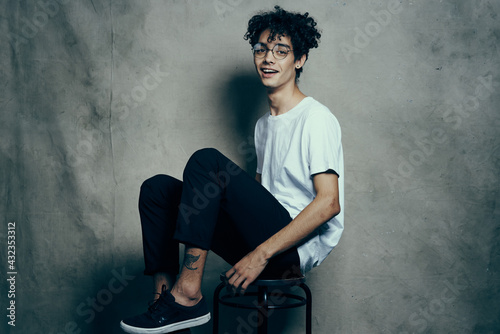 cute guy sitting on a chair curly hair smile lifestyle