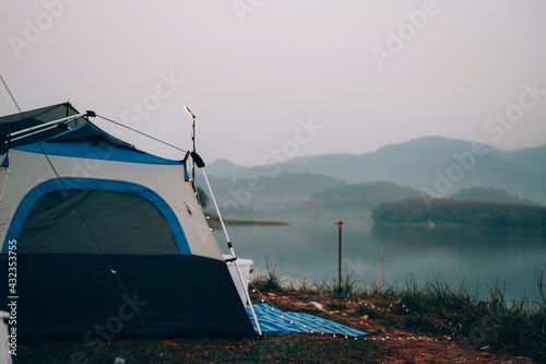 Camping tent on the camping area near the lake among the mountain and fog