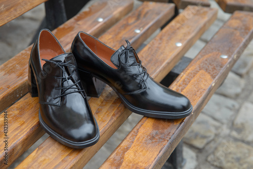 Women's leather boots close-up. black shiny oxford style shoes on a wooden bench photo
