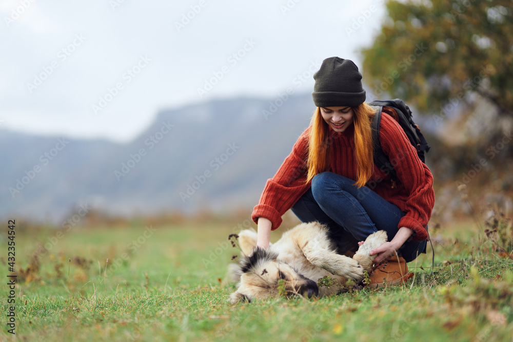 woman hiker with a backpack on nature in the mountains is played with a dog friendship woman hiker with a backpack on nature in the mountains is played with a dog friendship