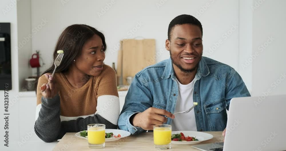 Businessman using laptop while having lunch with wife at home Businessman using laptop while having lunch with wife at home