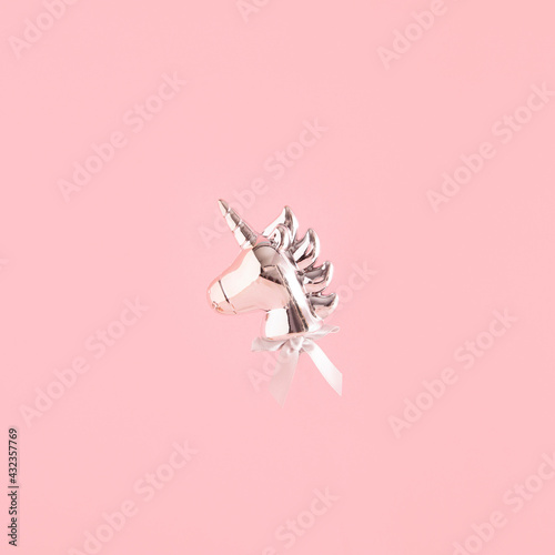 Silver unicorn balloon floats against pastel pink background