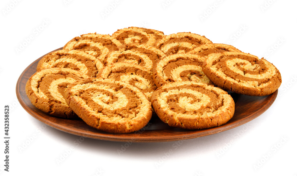 A clay plate with cookies is isolated on a white background. Cookies with a beautiful spiral pattern. A clay plate with cookies is isolated on a white background. Cookies with a beautiful spiral pattern.