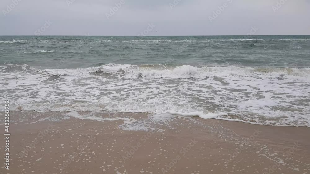 Seascape, sand, sea and gray clouds, seagulls soar above the waves. Stormy weather. Stormy sea. Seascape, sand, sea and gray clouds, seagulls soar above the waves. Stormy weather. Stormy sea.
