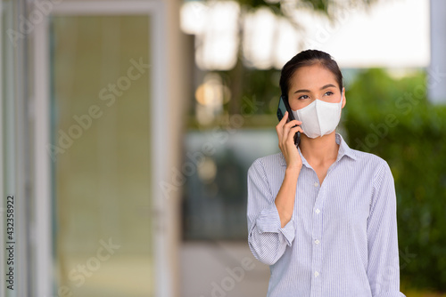 Woman wearing face mask to protect from coronavirus Covid-19 while talking on phone