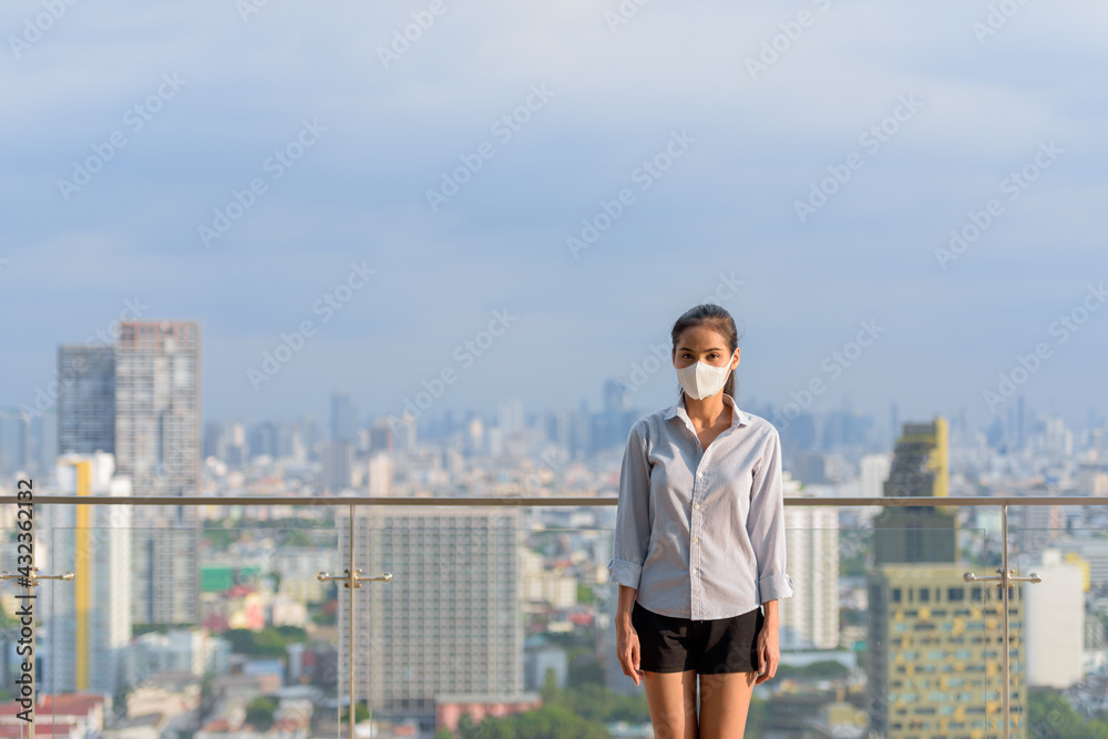 Asian woman wearing face mask to protect from coronavirus Covid-19 at rooftop outdoors Asian woman wearing face mask to protect from coronavirus Covid-19 at rooftop outdoors
