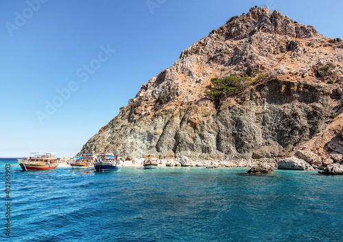 Pleasure boats with tourists docked on the coast of the island in the Mediterranean Sea