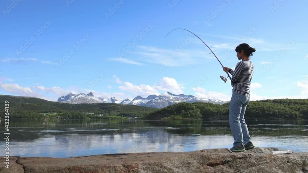 Woman caught a big fish on a fishing rod and can not pull it out of the water. Fishing on Fishing rod spinning in Norway. Fishing in Norway is a way to embrace the local lifestyle. Woman caught a big fish on a fishing rod and can not pull it out of the water. Fishing on Fishing rod spinning in Norway. Fishing in Norway is a way to embrace the local lifestyle.