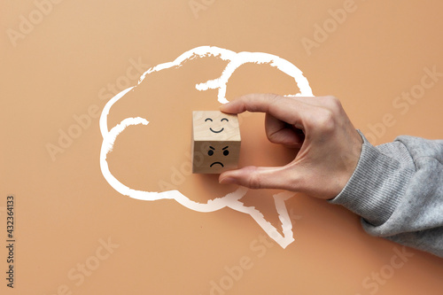 Fotobehang A cube in the silhouette of the brain with a picture of a smile on one side and an angry one on the other