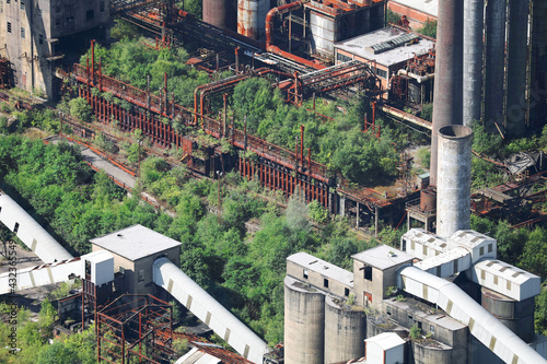 An aerial view, taken from a helicopter, of a derelict and abandoned industrial colliery site in The Valleys of South Wales. Tress and wildlife have taken over the old and now disused site.