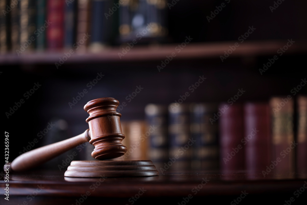 Lawyer office. Gavel on brown shining desk and collection of legal books in the bookshelf. Lawyer office. Gavel on brown shining desk and collection of legal books in the bookshelf.