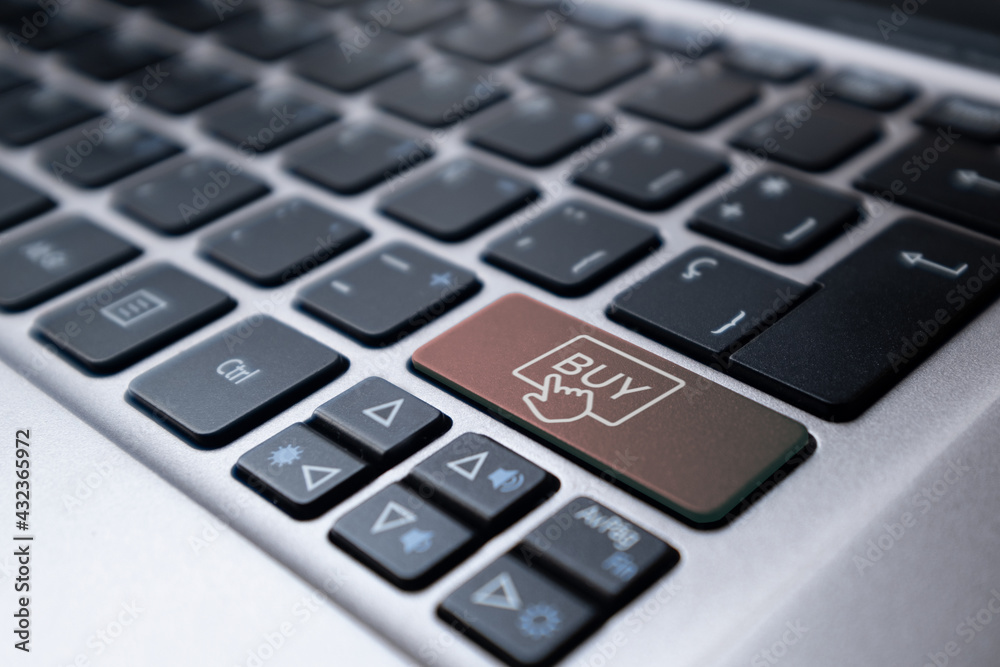 Laptop keyboard with a orange key with a buy symbol. E-commerce concept Laptop keyboard with a orange key with a buy symbol. E-commerce concept