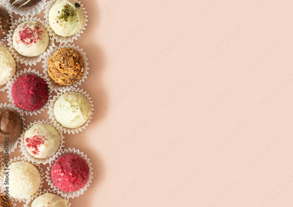 Naklejka premium Homemade candy close up on a pink background. Truffles with coconut, chocolate, karkade and nuts. Energy balls, superfood. Copy space, top view, flat lay.