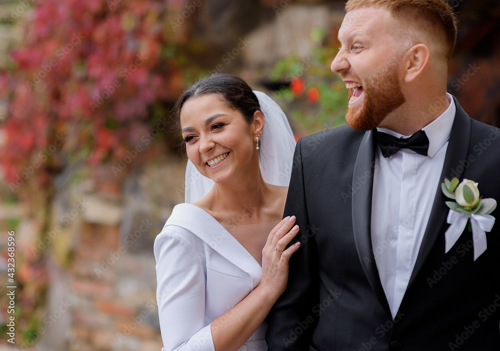 Side view of brunette bride and red-haired groom having fun and laughing. Concept of wedding couple Side view of brunette bride and red-haired groom having fun and laughing. Concept of wedding couple