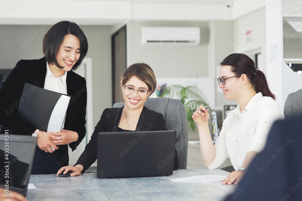 Three young successful business women in the office, together, happily working on a project Three young successful business women in the office, together, happily working on a project