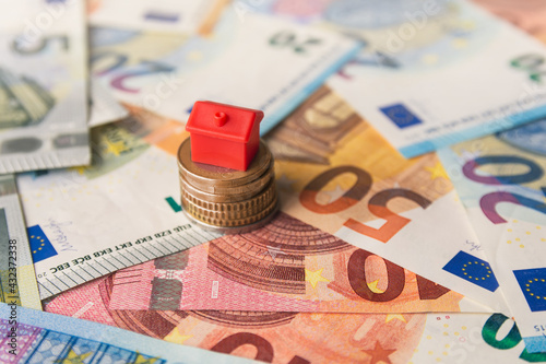 Miniature colorful red house on stack coins and euro banknotes. Finance and property investment concept. Real estate investment.
