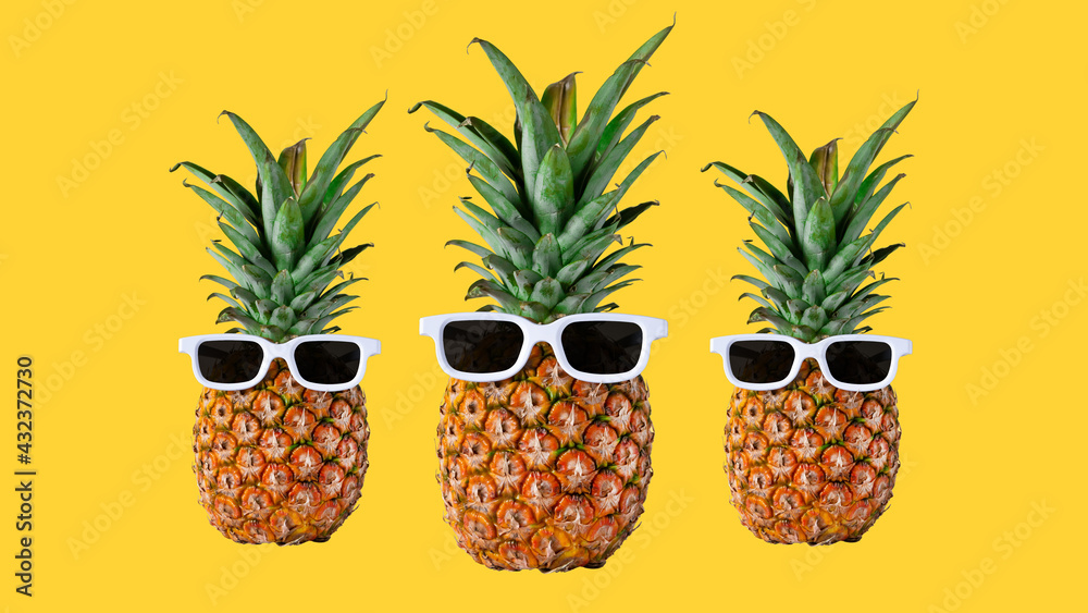 Tree pineapples hipster in sunglasses isolated on yellow background, stylish fruits. Summer tropical pineapple. Creative art vacation concept.