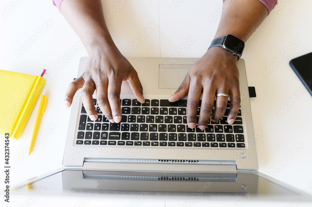 A male hands on the laptop keyboard. Top view an African-American guy is typing email, programmer is develops software, cropped photo, a face is not visible, close-up picture - obrazy, fototapety, plakaty 