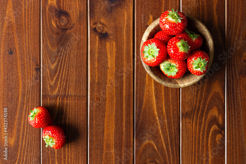 Perfectly red strawberries in wooden bowl on dark rustic wood; natural fresh summer berries; healthy snack photo