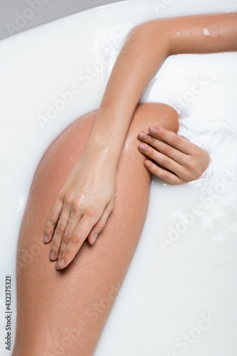 cropped view of woman touching hip while enjoying milk bath.
