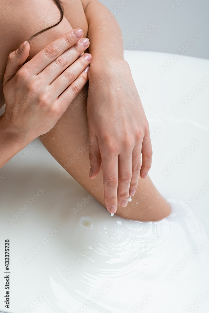 partial view of woman touching leg while taking milk bath.