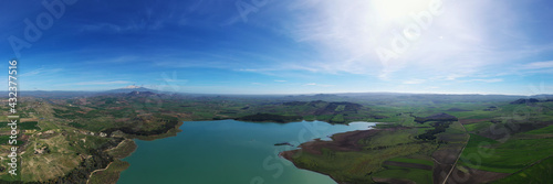 180 degree aerial photo of Ogliastro lake in the heart of Sicily with Etna view. Place of great naturalistic value surrounded by hills planted with cereals. A destination for migratory bird species.