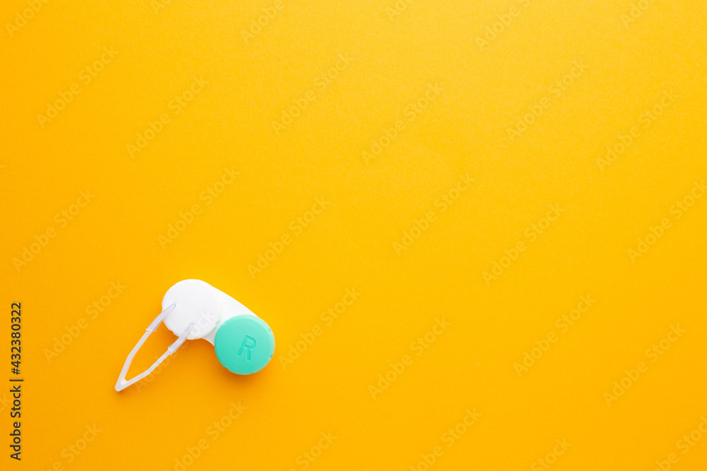 Accessories for contact lenses: a solution container, tweezers. Yellow background Accessories for contact lenses: a solution container, tweezers. Yellow background
