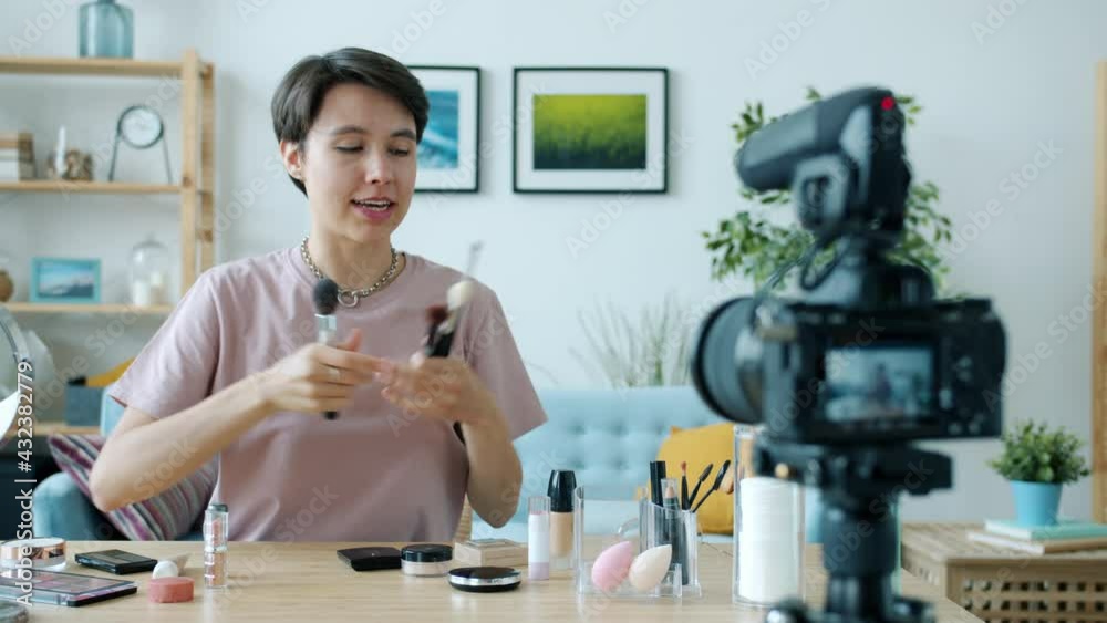 Cheerful female vlogger is recording tutorial about make-up talking and gesturing using camera at home. Beauty professionals and vlogging concept. Cheerful female vlogger is recording tutorial about make-up talking and gesturing using camera at home. Beauty professionals and vlogging concept.