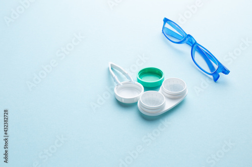Glasses and accessories for contact lenses: a container for lenses and tweezers on a blue background