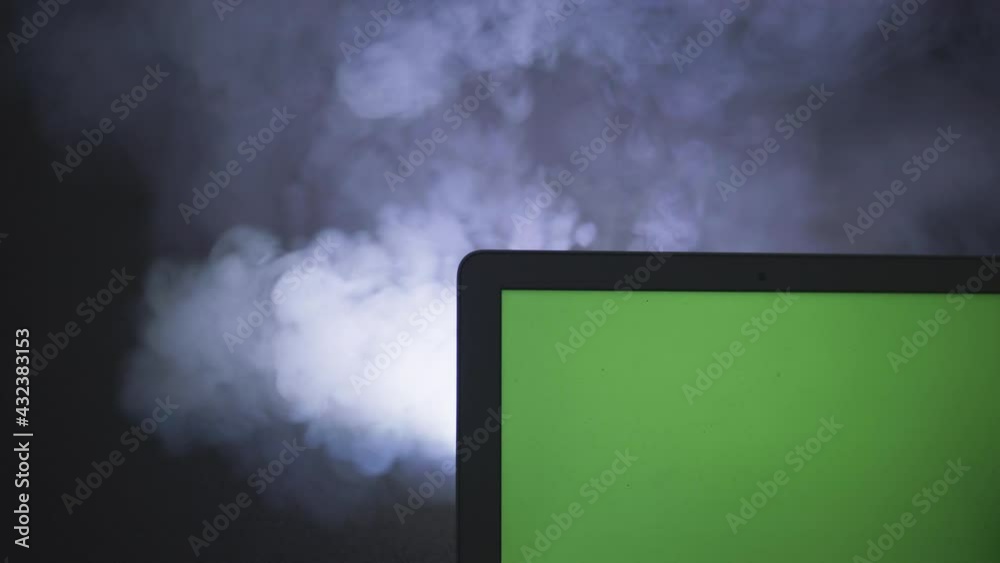 Ordinateur portable avec fond vert sur fond noir isolé avec de la fumée 